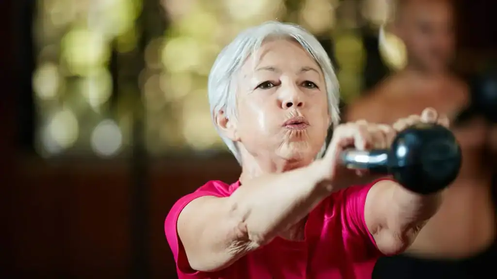 Toning Arms After 60: Empowering Womens Fitness Through Effective Weight Training 1 Older woman doing weight training Harlow to help her strength and longevity
