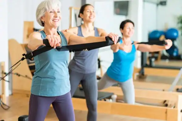 Toning Arms After 60: Empowering Womens Fitness Through Effective Weight Training 2 older woman doing weight training Harlow and resistance in the gym to tone upper arms