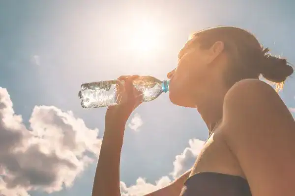 Hydration: The Secret Ingredient for a Toned Stomach and Enhanced Fitness 3 Image of woman drinking water to hydrate Harlow after run.