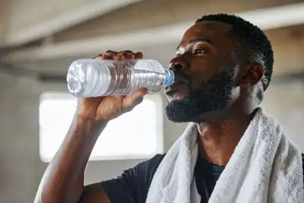 Image of man drinking water to improve hydration Harlow after work out.